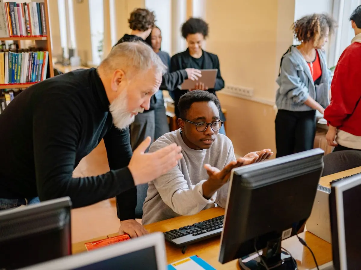 Mentor ayudando a un estudiante en el computador